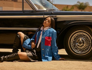 Bustle cover star Camila Cabello poses against a vintage car wearing a blue and red Louis Vuitton ja...