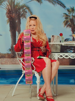 Jennifer Coolidge sitting on a chair and holding ten lottery tickets 