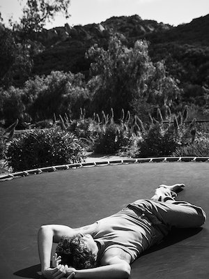 Black and white photo of Charlie Puth in a EYTYS tank and jeans laying on a trampoline
